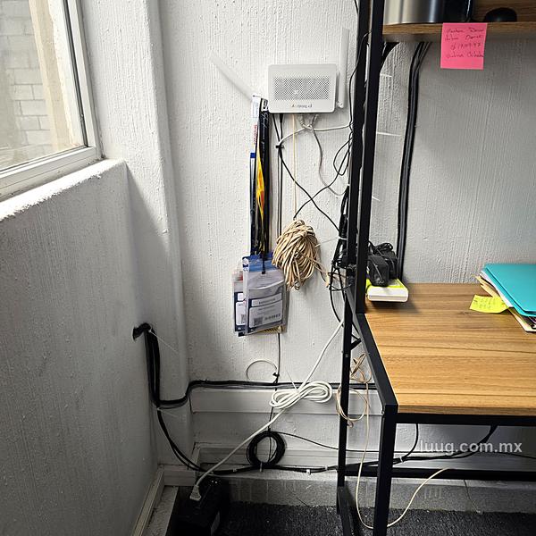 Módem y cables sueltos colgando en la pared de una oficina